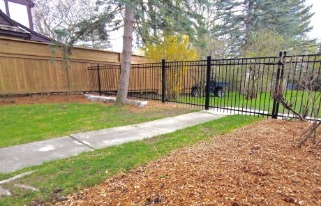 New wrought iron black metal fence and armour stone retaining wall in guelph with would privacy fence