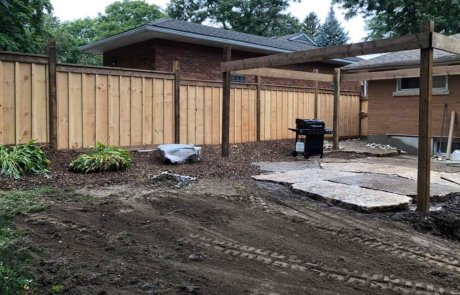 Backyard Large natural stone flagstone with pergola and strong wood fence and pond water feature